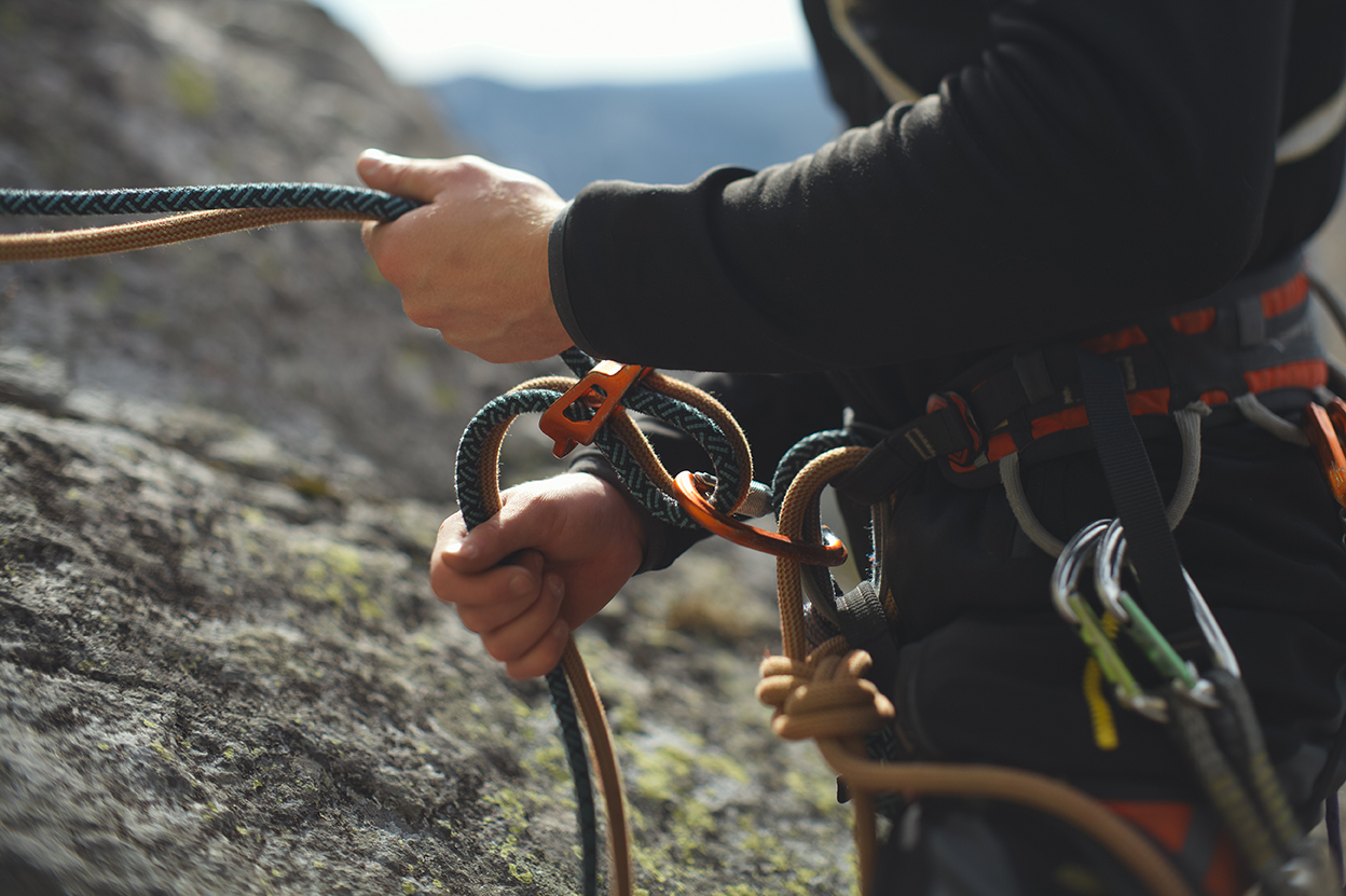 Climber with ropes and harness on a rock face